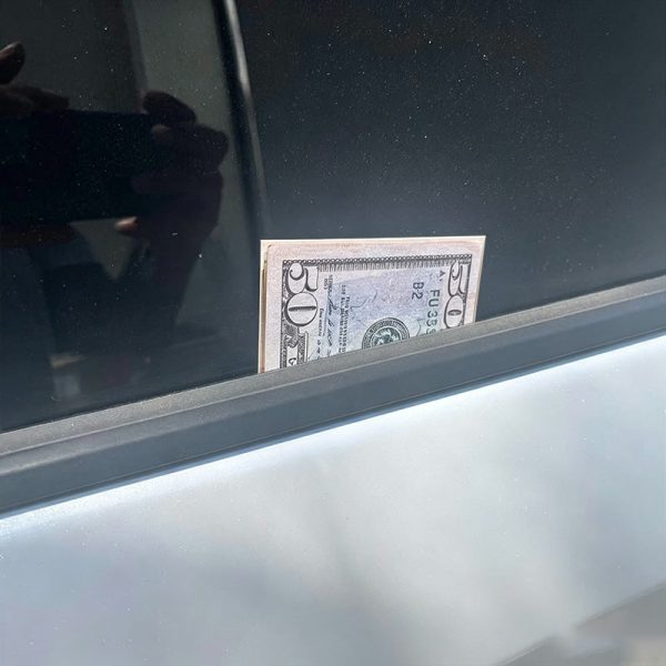 The prank card looking like a banknote under a windscreen wiper